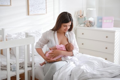 Happy young mother breastfeeding her newborn baby at home