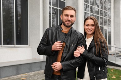 Happy couple wearing stylish leather jackets on city street. Autumn walk