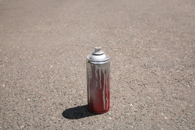Photo of Used can of spray paint on asphalt road, space for text. Graffiti supplies