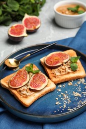 Tasty toasts served with fig, peanut butter and walnuts on light grey marble table
