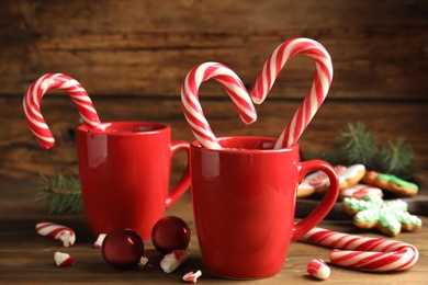 Cups of hot chocolate with candy canes and Christmas decor on wooden table