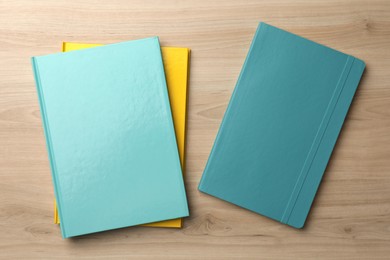 Different colorful planners on wooden table, flat lay