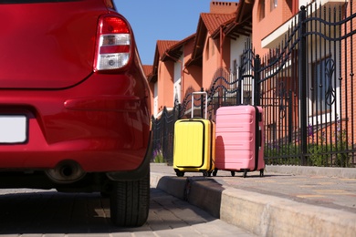 Color suitcases near family car in city. Summer vacation