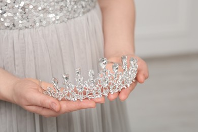 Photo of Woman holding luxurious tiara indoors, closeup view