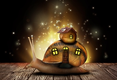 Fantasy world. Magic snail with its shell house moving on wooden surface surrounded by fairy lights
