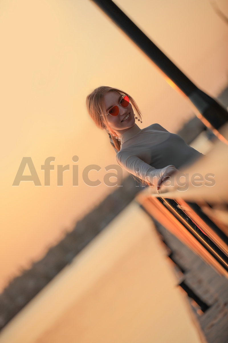 Silhouette of young woman leaning on railing at sunset