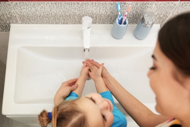 Mother and daughter washing hands in bathroom at home, above view