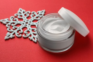 Photo of Jar of hand cream and snowflake on red background. Winter skin care