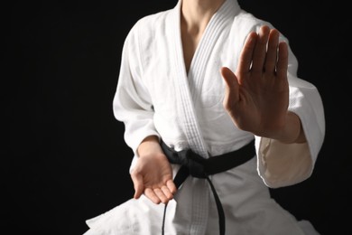 Photo of Man wearing keikogi and black belt on dark background, closeup. Martial arts uniform