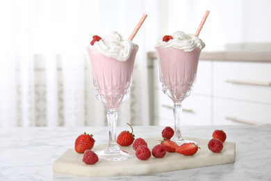 Tasty milk shake with whipped cream and fresh berries on white marble table