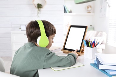 Cute little boy with modern tablet studying online at home. E-learning