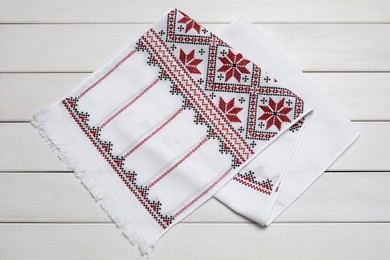 Beautiful rushnyk on white wooden table, top view. Ukrainian national embroidery