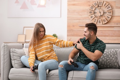 Emotional young couple playing video games at home