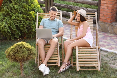 Photo of Happy couple relaxing in deckchairs at backyard