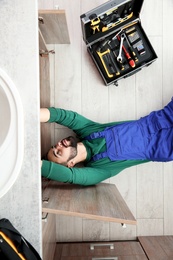 Male plumber repairing kitchen sink, top view