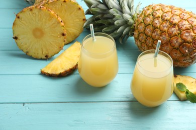 Photo of Delicious pineapple juice and fresh fruit on light blue wooden table