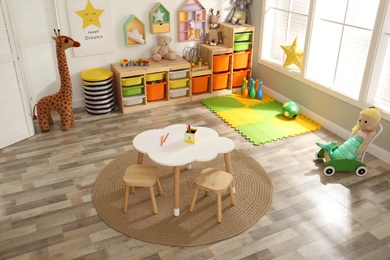 Stylish playroom interior with modern furniture and soft toys, above view