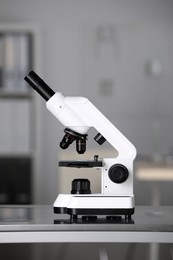 Photo of Modern medical microscope on metal table in laboratory