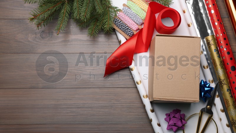 Box, wrapping paper and scissors on wooden table, flat lay. Space for text