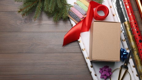 Photo of Box, wrapping paper and scissors on wooden table, flat lay. Space for text
