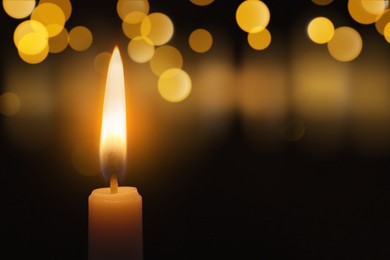 Image of Wax candle burning in darkness, bokeh effect. Christmas Eve