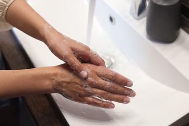 Woman washing hands in sink, closeup view