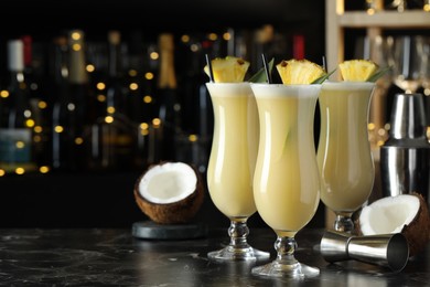 Photo of Tasty Pina Colada cocktails on black marble bar countertop, space for text