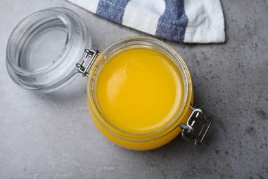 Glass jar of Ghee butter on grey table, top view