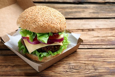 Delicious burger in cardboard box on wooden table