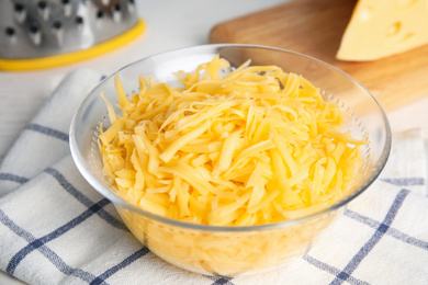 Delicious grated cheese in glass bowl on table, closeup