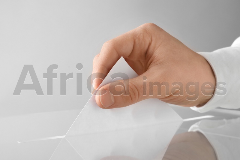 Man putting his vote into ballot box on light background, closeup