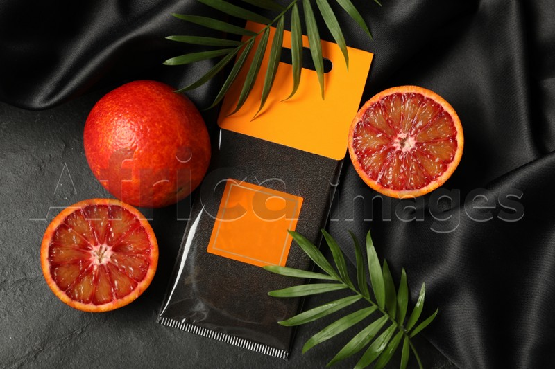 Scented sachet, red oranges and leaves on black table, flat lay