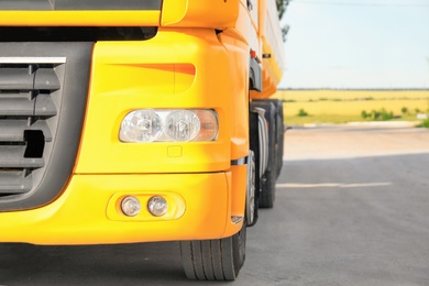 Modern yellow truck parked on country road, closeup. Space for text