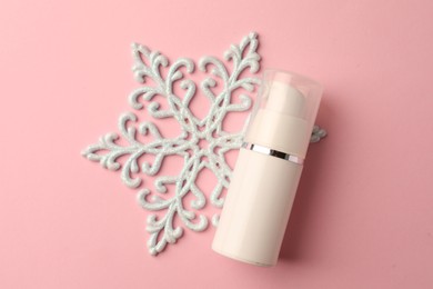 Photo of Winter skin care. Hand cream and snowflake on pink background, top view