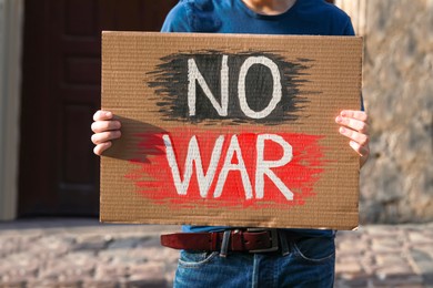 Man holding poster with words No War on city street, closeup
