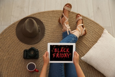 Woman using tablet with Black Friday announcement while sitting on floor at home, above view