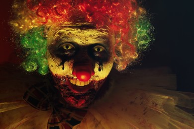 Terrifying clown in darkness, closeup. Halloween party costume