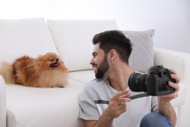 Professional animal photographer taking selfie with beautiful Pomeranian spitz dog indoors