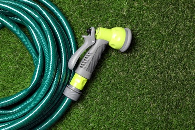 Watering hose with sprinkler on green grass, top view. Space for text