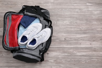 Grey gym bag with sports stuff on wooden  background, top view. Space for text