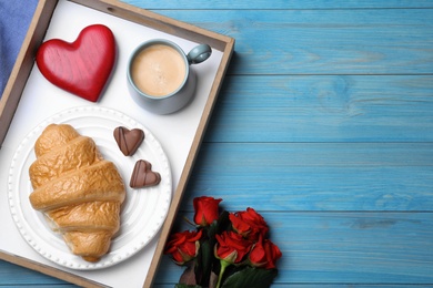 Romantic breakfast and roses on blue wooden table, flat lay with space for text. Valentine's day celebration