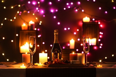 Romantic dinner table setting with burning candles and festive lights