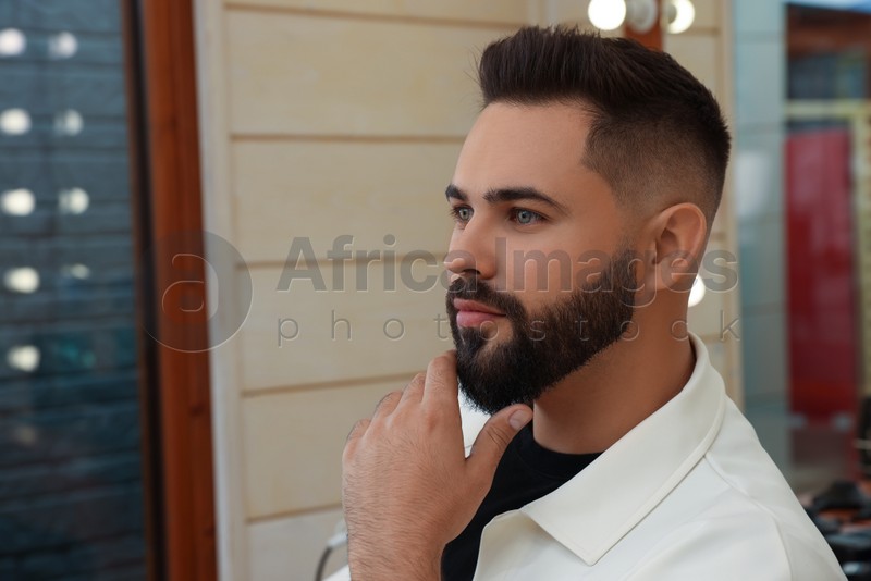 Young man with fresh haircut and groomed beard in barbershop