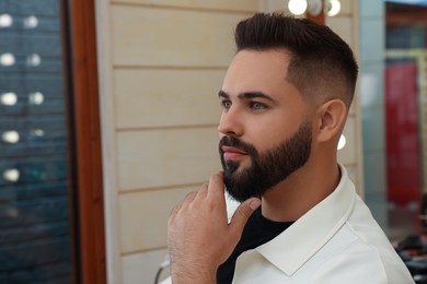 Young man with fresh haircut and groomed beard in barbershop