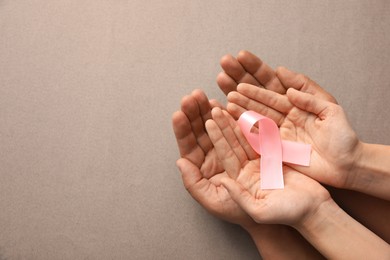 Couple holding pink ribbon on grey background, top view. Breast cancer awareness concept