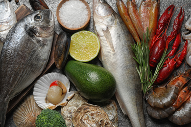 Fresh fish and different seafood on grey table, top view