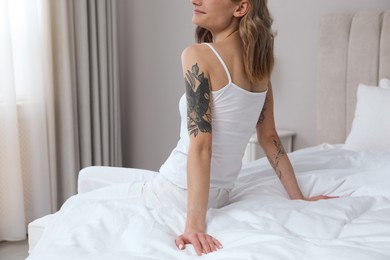 Beautiful woman with tattoos on arms in bedroom, closeup