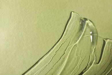 Transparent cosmetic gel on olive background, top view. Space for text