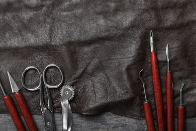 Leather sample and craftsman tools on grey stone background, flat lay