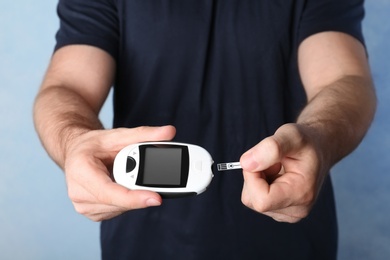 Man holding glucometer on color background. Diabetes test
